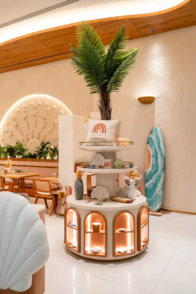 Round display stand with a palm, a surfboard and arched lit niches