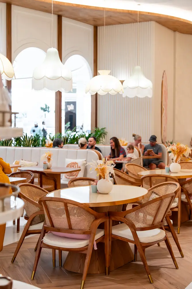 Round wooden seating with cushioned rattan chairs by the arched windows
