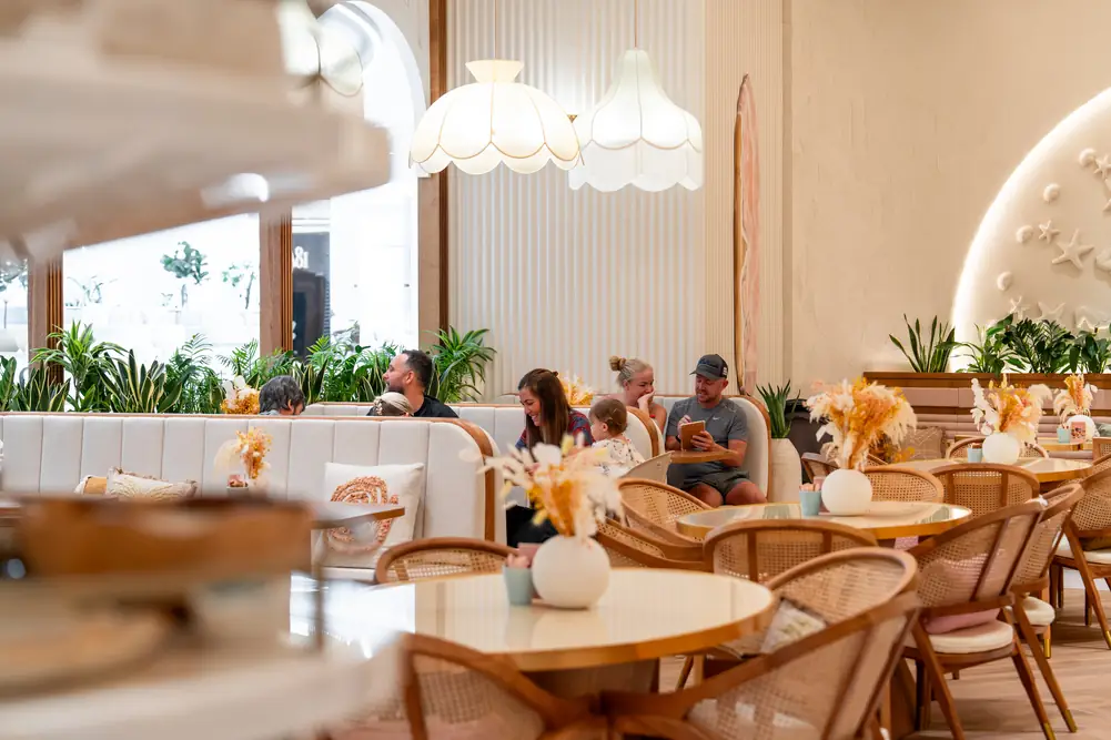 Dining room with white pleated lamps, rattan chairs and dried-flower centrepieces