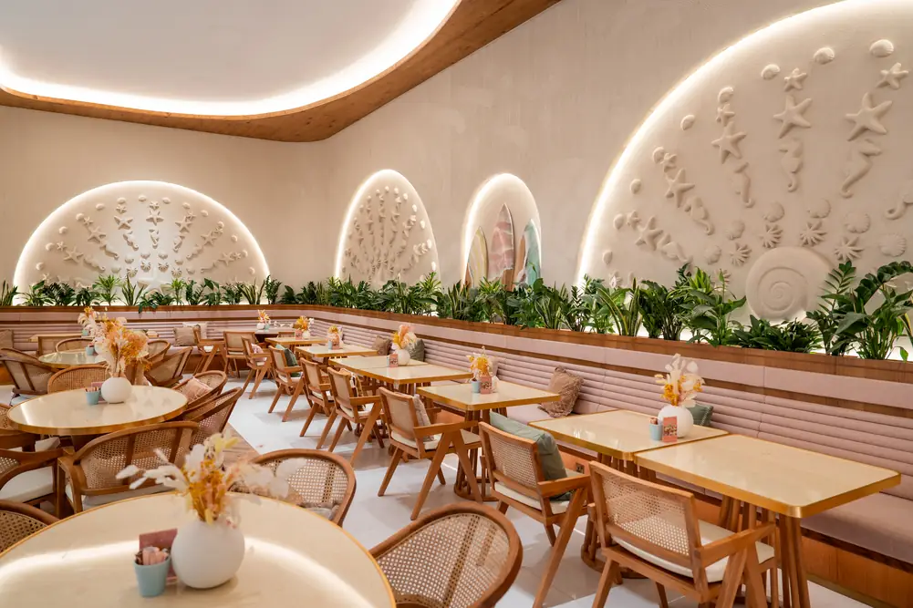 Dining room with carved shell wall, white sofas and rattan chairs